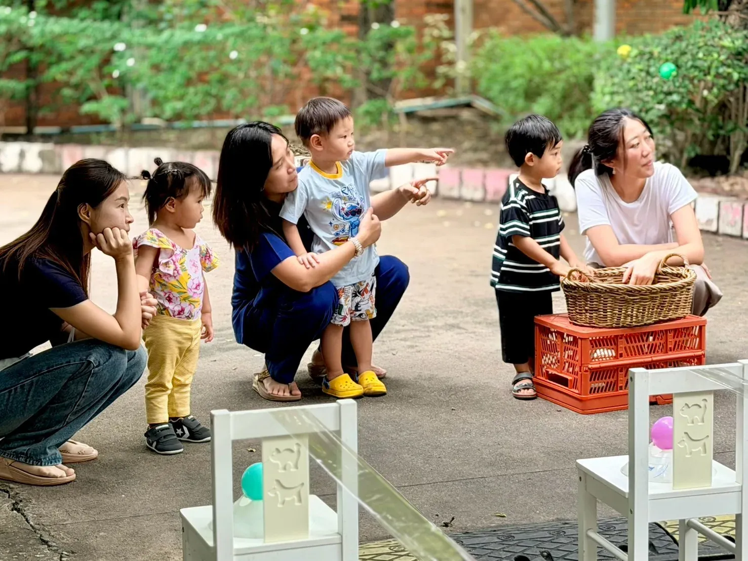 Children and parents watching and pointing as a ball rolls down a ramp