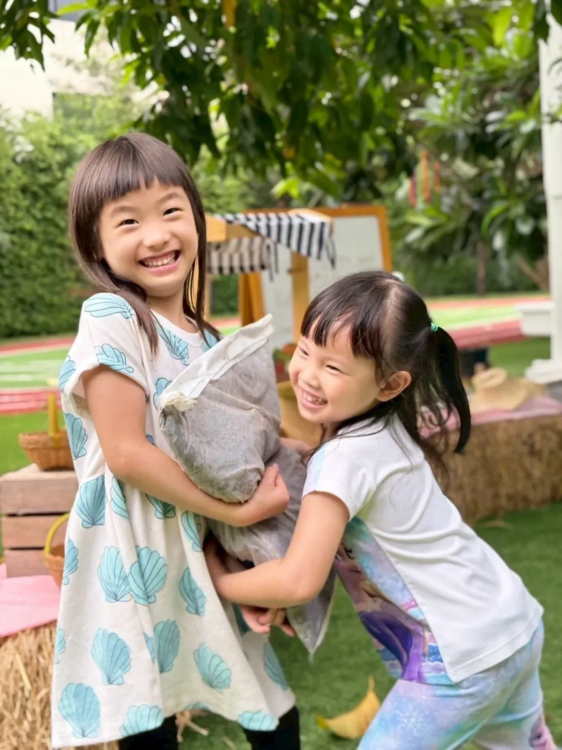 Two girls laughing as they carry a sack of soil to the beds