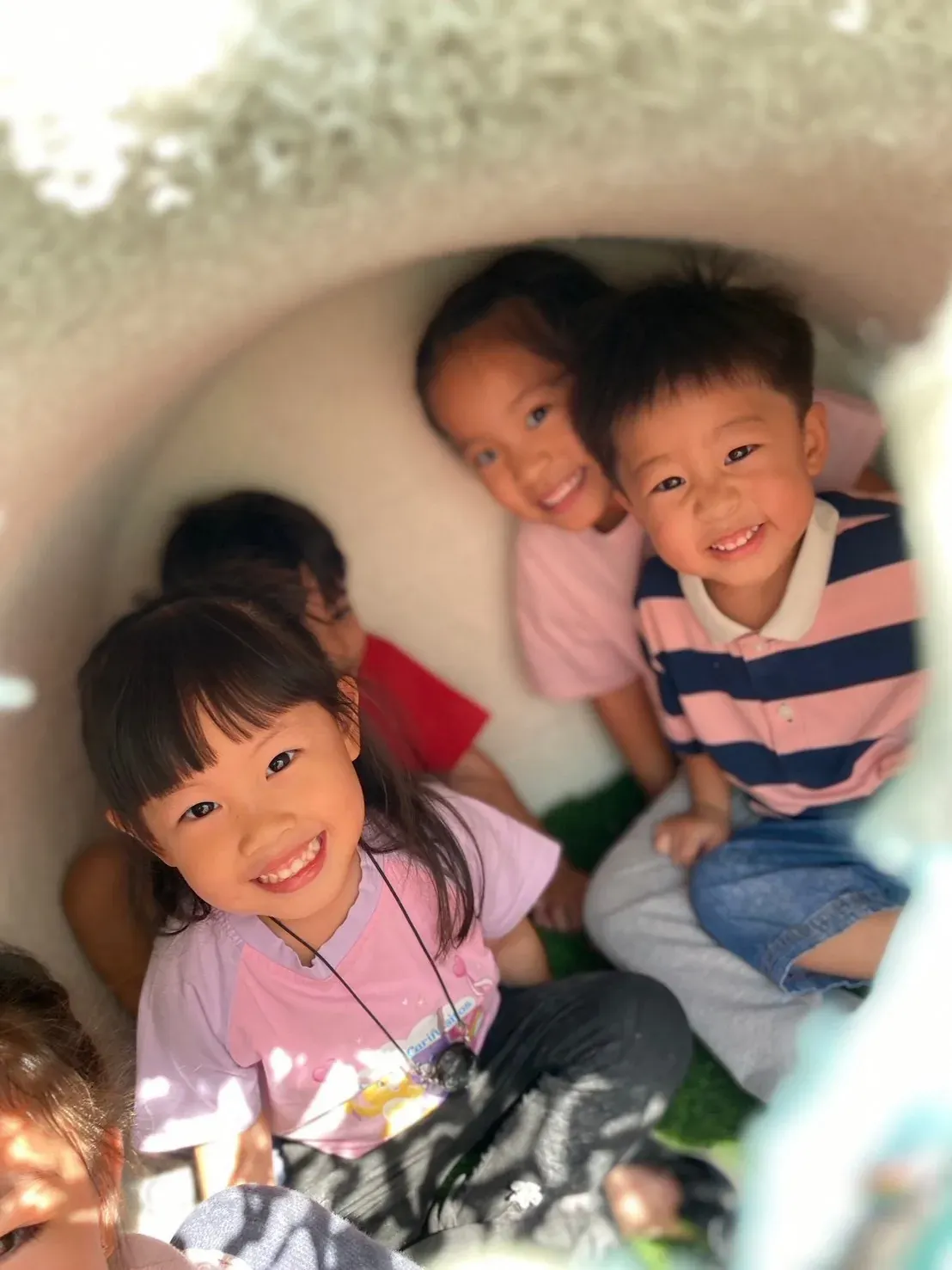 Children smiling out from inside the play tunnel
