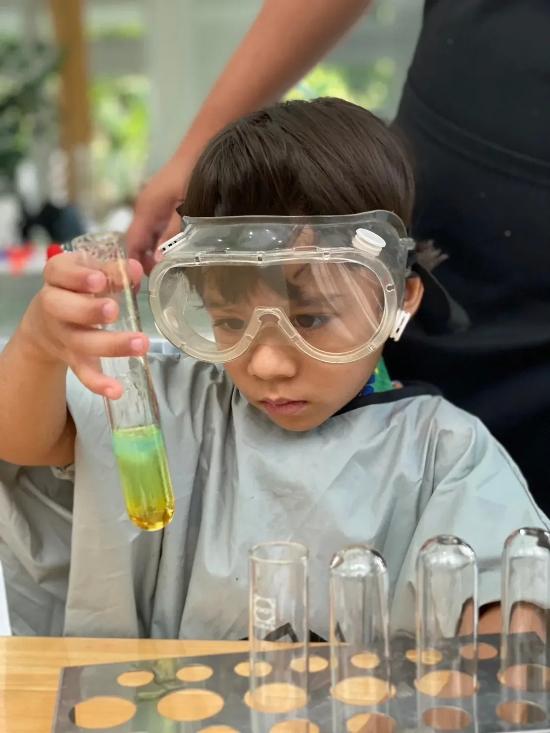 A boy in goggles studying the coloured layers in a test tube