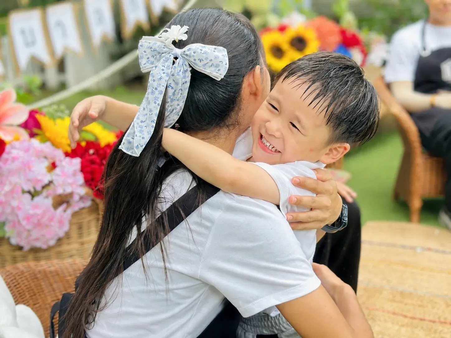 A smiling boy wrapped in a warm hug at a school celebration