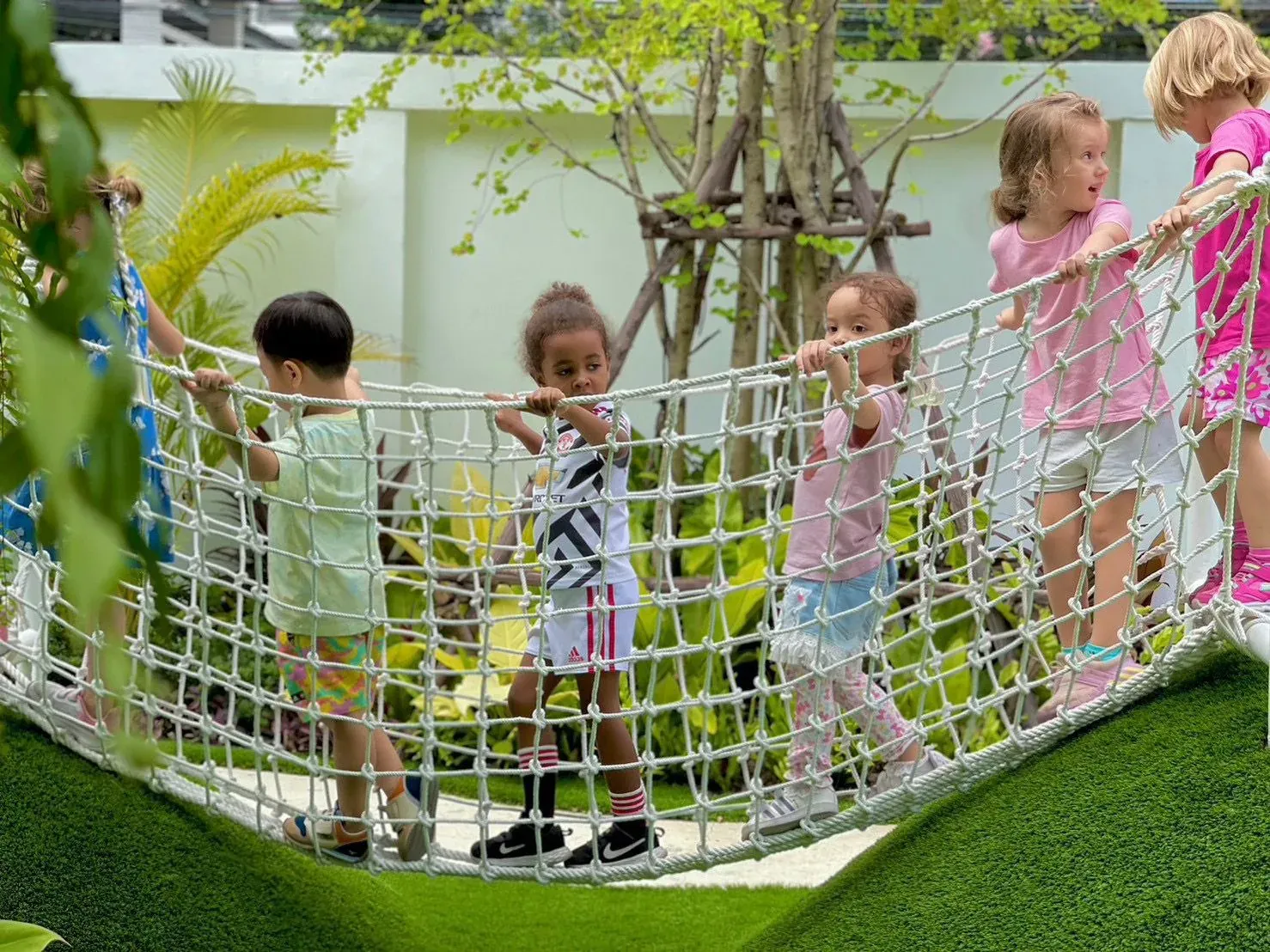 Children crossing the rope bridge together in the KIMS garden